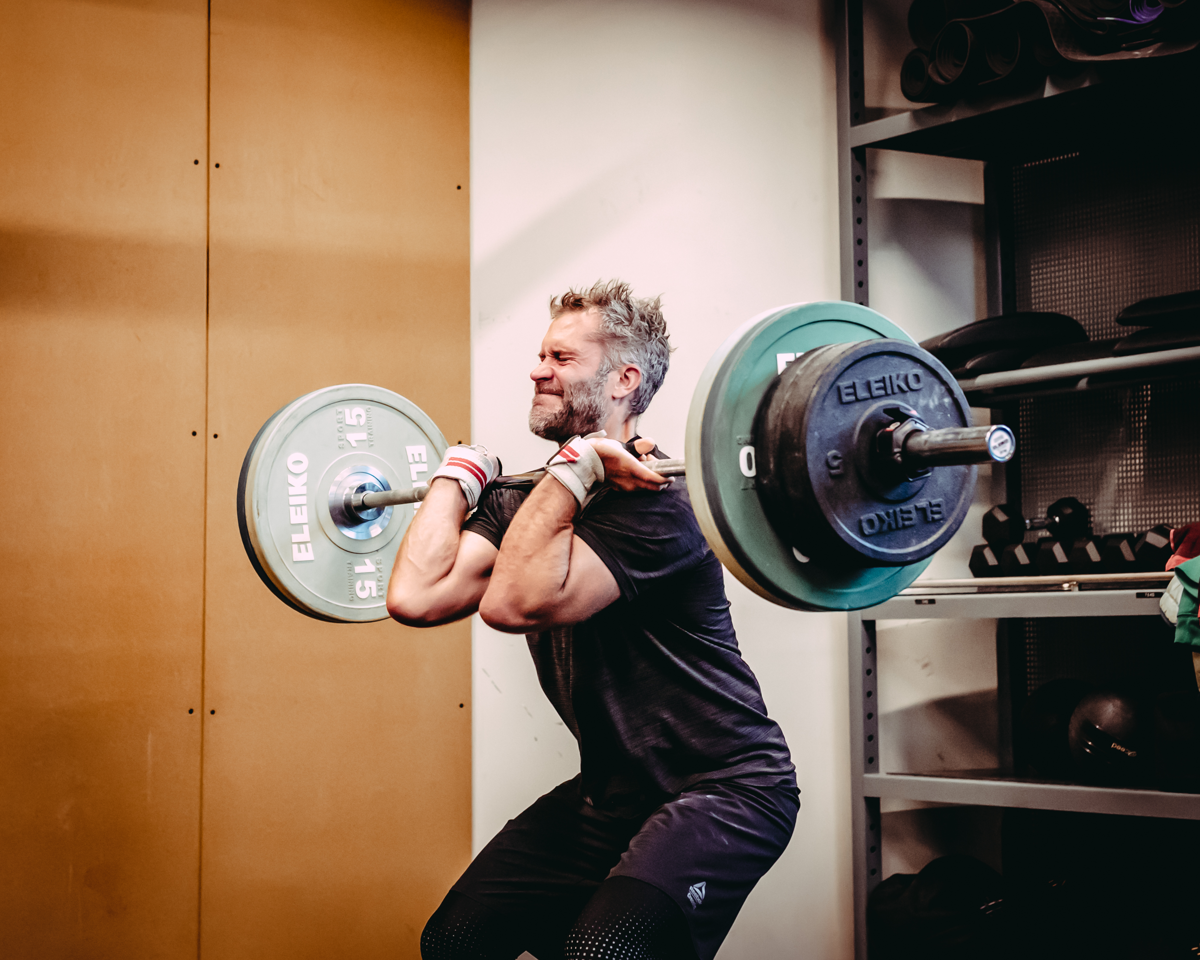 Mature man performing functional strength training with heavy barbell