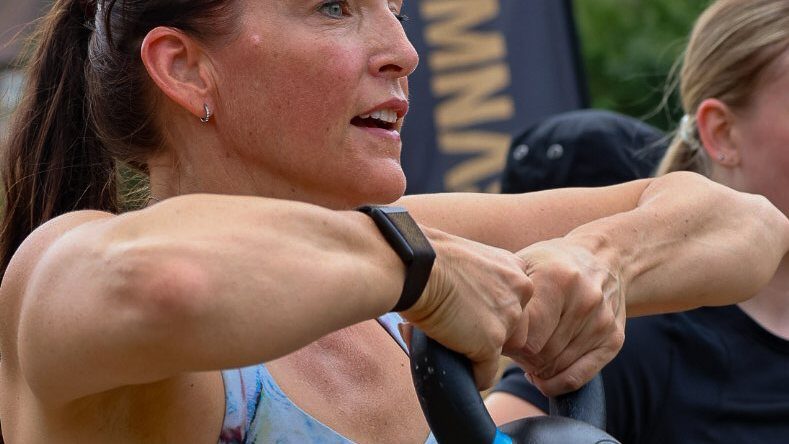 Member mid-swing with a kettlebell, focused and driving through the movement