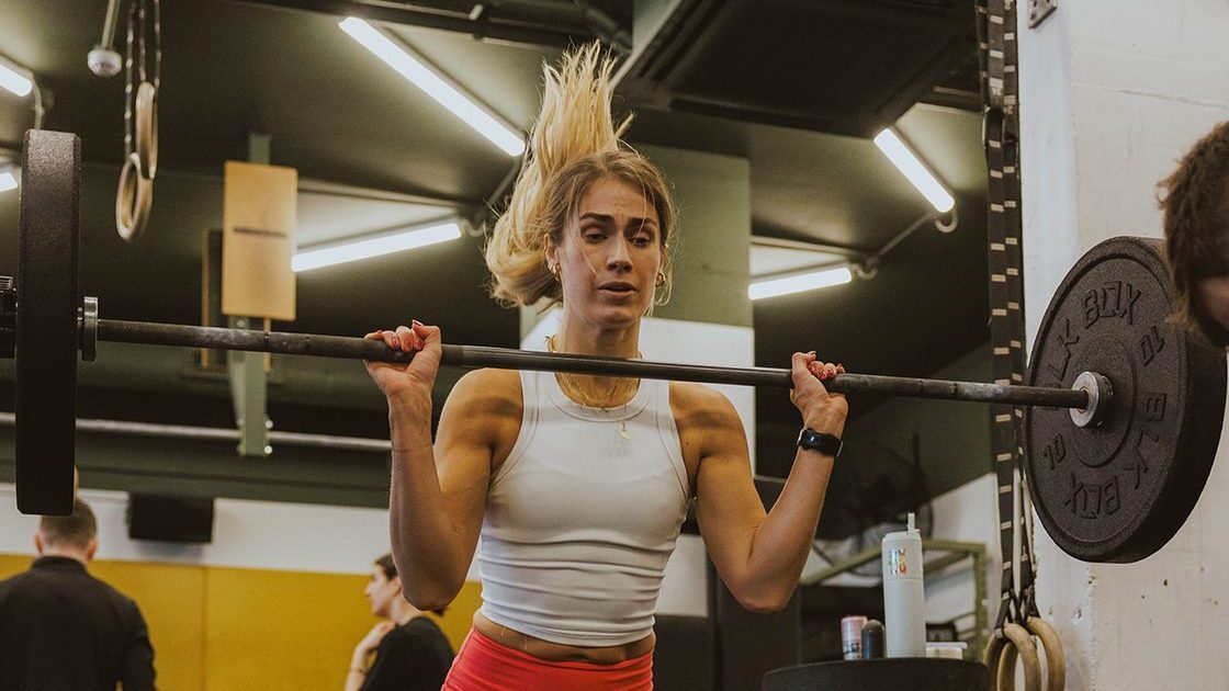 Woman holding a barbell on her shoulders during a coached strength session